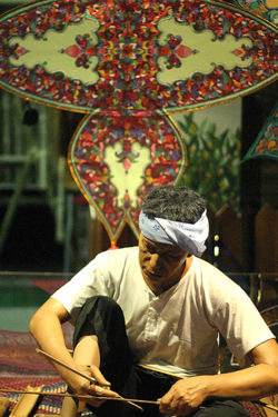 Making traditional Wau jala budi kite, Malaysia. The bamboo frame is covered with plain paper and then decorated with multiple layers of cut-outs of paper and foil.