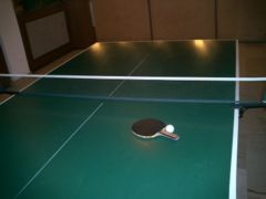 A standard table tennis table, together with a racket and ball.