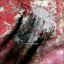 A satellite false-color image of Baghdad, taken March 31, 2003. The image shows smoke rising from pools of burning oil spread along "Canal Road" and other locations. Ditches full of oil were created shortly before the war to obscure visibility (black) and vegetation (red)