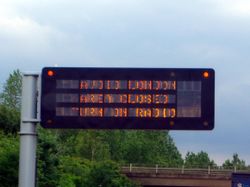 Sign on M25 ring road reads:  AVOID LONDON  AREA CLOSED  TURN ON RADIO