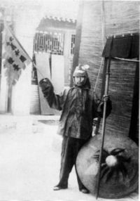 A Boxer rebel. His banner says (in translation) "By Imperial Order - Boxer Supply Commissariat".