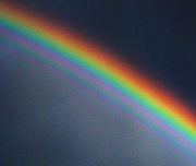 A contrast-enhanced photograph of a supernumerary rainbow, with additional green and purple arcs inside the primary bow.