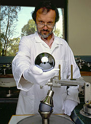 Shown above, one of the master opticians at the Australian Centre for Precision Optics (ACPO) is holding a 1 kg, single-crystal silicon sphere for the Avogadro project. These spheres are among the roundest man-made objects in the world. If the best of these spheres were scaled to the size of Earth, its high point—a continent-size area—would gently rise to a maximum elevation of only 2.4 meters above “sea level”.