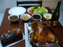 Roast turkey served with salad, sauces and sparkling juice. On the left is a log cake.