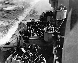 A kamikaze (just left of center near the top border), a Mitsubishi Zero in this case, about to hit the Missouri (1944)