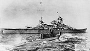 U-47 returns to port after sinking HMS Royal Oak in October 1939. The battlecruiser Scharnhorst is seen in the background.