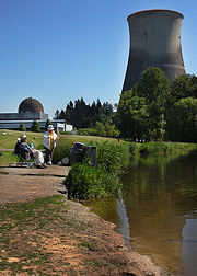 A couple of fishermen near the decommissioned Trojan Nuclear Power Plant. The reactor dome is visible on the left, and the large cooling tower on the right.
