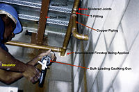 Copper piping system with intumescent firestop being installed by an insulator in Vancouver, Canada.