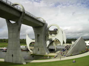 The Falkirk Wheel in action. The wedge-shaped building on the right is the visitors' centre.  Click on image to view the Docking Pit at the bottom canal.