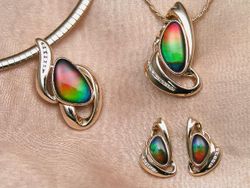 Fine ammolite jewelry by Korite International. The ammolite gems are triplets, as evidenced by their convex profiles, and are set in 14 karat (58%) gold with diamond accents. Ammolite is best used in pendants, earrings, and brooches due to its fragility.