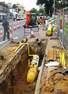 Polyethylene gas main being laid in a trench.
