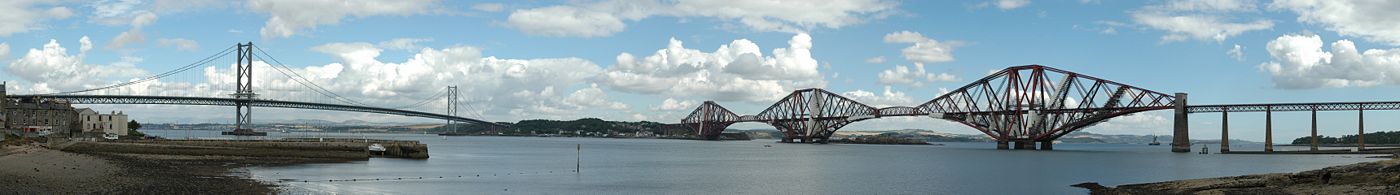 A panoramic view of the Forth Bridges viewed from the south bank of the Firth of Forth. The older rail bridge is to the right, east of the newer road bridge.