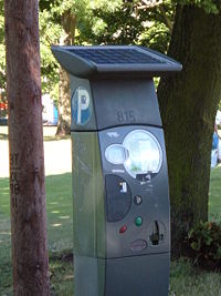 A solar panel on top of a parking meter. Note that this particular installation is shaded, and may not perform as desired.