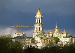 An old and a modern city. A construction crane and the towers of the Kiev Monastery of the Caves.