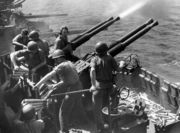 Bofors 40 mm anti-aircraft guns on a MK 12 quadruple mount fire from the deck of the USS Hornet in World War II.