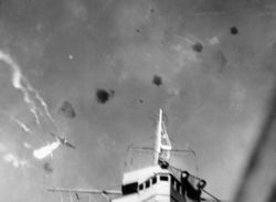A Japanese "Val" dive bomber, believed to be piloted by Yoshihiro Iida, is shot down by anti-aircraft fire directly over Enterprise.