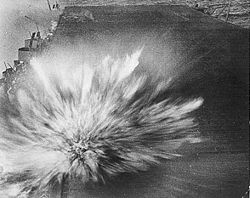 The third and last bomb, dropped by an aircraft piloted by Kazumi Horie who died in the attack, hits Enterprise, causing minor damage.  Smoke from the first two bomb hits can be seen in the upper left of the picture.