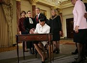 Rice signs official papers after receiving the oath of office during her ceremonial swearing in at the Department of State. Watching on are, from left, Laura Bush, Justice Ruth Bader Ginsburg, President George W. Bush and an unidentified family member.