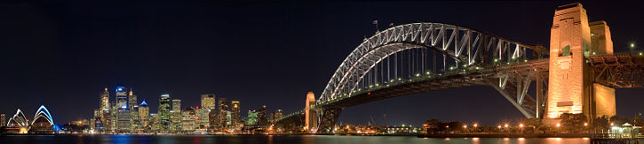 A panorama of Sydney Harbour at night, with the Sydney Opera House on the left, the central business district in the image centre and Sydney Harbour Bridge on the right
