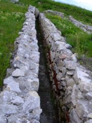 A sanitary channel at Potaissa. It is placed cross-slope  with a slight decline and then exits down-slope.