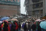 Rain was among the many problems that occurred during the aftermath of the earthquake. Here, a group of onlookers examine a collapsed building in the rain.