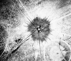 An aerial photograph of the "Trinity" crater shortly after the test. The small crater in the southeast corner was from the earlier test explosion of 100 tons of TNT.