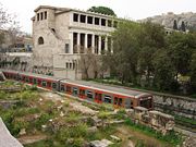 An ISAP train (Green Line) passes by the Stoa of Attalus in central Athens.