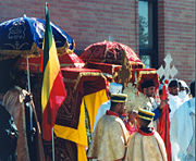 Ethiopian Orthodox clergymen lead a procession in celebration of Saint Michael. The priests carry ornately covered Tabota around the church's exterior, assisted by deacons holding liturgical umbrellas.