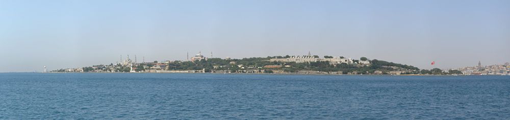 Panoramic view of the historic peninsula of Istanbul, looking westwards from the southern entrance of the Bosporus at the Sea of Marmara. From left to right, the Sultan Ahmed Mosque, the Hagia Sophia and the Topkapı Palace are seen, along with the surviving sections of the Sea Walls of Constantinople. The Galata Tower is seen at the far right of the picture, across the Golden Horn. The arches and vaults of the Byzantine-era Mangana (Armoury) and the Hagios Georgios Monastery which was located inside it are seen between the Blue Mosque and the Hagia Sophia, near the shore. The dome of the Hagia Irene can be seen to the right of the Hagia Sophia.