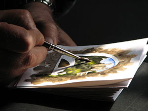 Artist working on a watercolor using a round brush.
