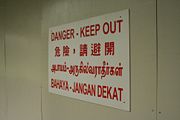 Construction site sign showing Singapore's four official languages: English, Mandarin, Tamil, and Malay.