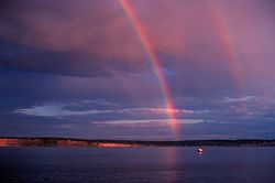 Primary and secondary rainbows are visible, as well as a reflected primary and a faintly visible reflected secondary.