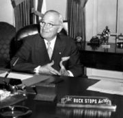 President Harry Truman with "The Buck Stops Here" sign on his desk