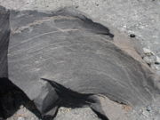 Basalt (an extrusive igneous rock in this case); light colored tracks show the direction of lava flow.