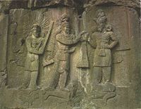 Relief from Taq-i Bostan showing Ardashir II at the center receiving his crown from Ahura Mazda. The two stand on a prostrate enemy. At the left is Mithra as a priest, wearing a crown of sun-rays, holding a priest's barsam, and standing on a sacred lotus