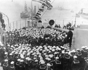 Roosevelt (on the 12" gun turret at right) addresses the crew of USS Connecticut (BB18) in Hampton Roads, Virginia, upon her return from the Fleet's cruise.