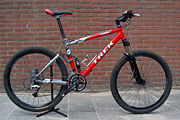 This mountain bicycle features oversized tires, a full-suspension frame, two disc brakes and handlebars oriented perpendicular to the bike's axis