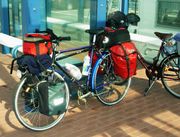 Touring bicycle equipped with head lamp, pump, rear rack, fenders/mud-guards, water bottles and cages, and numerous saddle-bags.