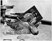 With a torn picture of his Führer beside his clenched fist, a dead general of the Volkssturm lies on the floor of city hall, Leipzig, Germany. He committed suicide rather than face U.S. Army troops who captured the city.