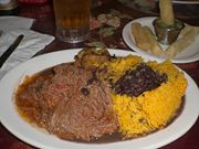 Authentic Cuban dish of ropa vieja, black beans, yellow rice, plantains and fried yuca with beer