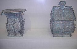 Left: Bronze 方樽 fāngzūn ritual wine container dated about 1000 BCE. The written inscription cast in bronze on the vessel commemorates a gift of cowrie shells (then used as currency in China) from someone of presumably elite status in 周 Zhōu Dynasty society. Right: Bronze 方彝 fāngyí ritual container dated about 1000 BCE. A written inscription of some 180 Chinese characters appears twice on the vessel. The written inscription comments on state rituals that accompanied court ceremony, recorded by an official scribe.