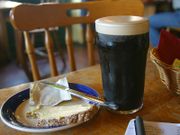 A pint of Guinness with a slice of brown bread and butter.