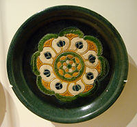 A rounded ceramic plate with "three colors" (sancai) glaze design, 8th century