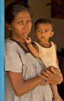 A mother and her child stand in the doorway of their new home in Komari, Sri Lanka