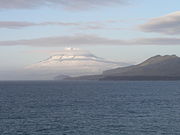 Snow-covered Beerenberg beyond coastal hills