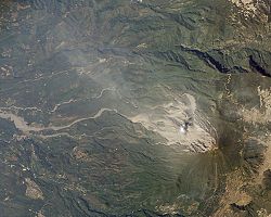 Steam rises from Santiaguito. The area of the flank destroyed by the 1902 eruption can be clearly seen. Lahar deposits snake down river valleys to the left of the image